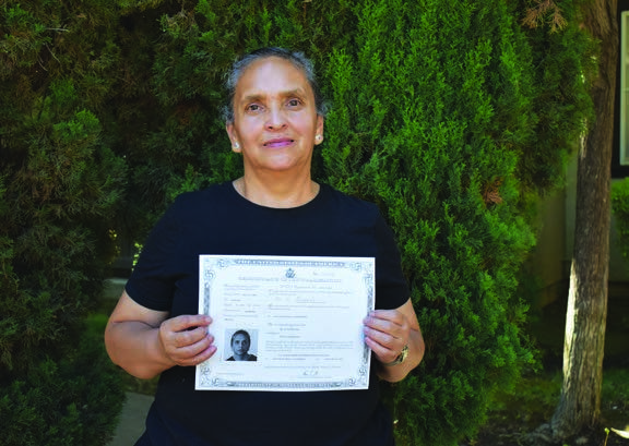 Maria holding her citizenship certificate in the 2021 annual report.