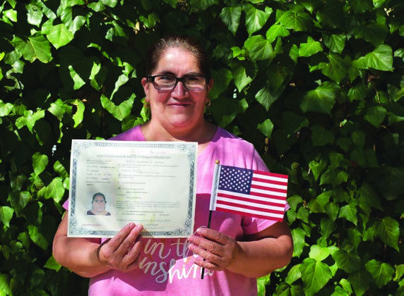 Mireya holding her citizenship certificate and a small American flag in the 2021 annual report.