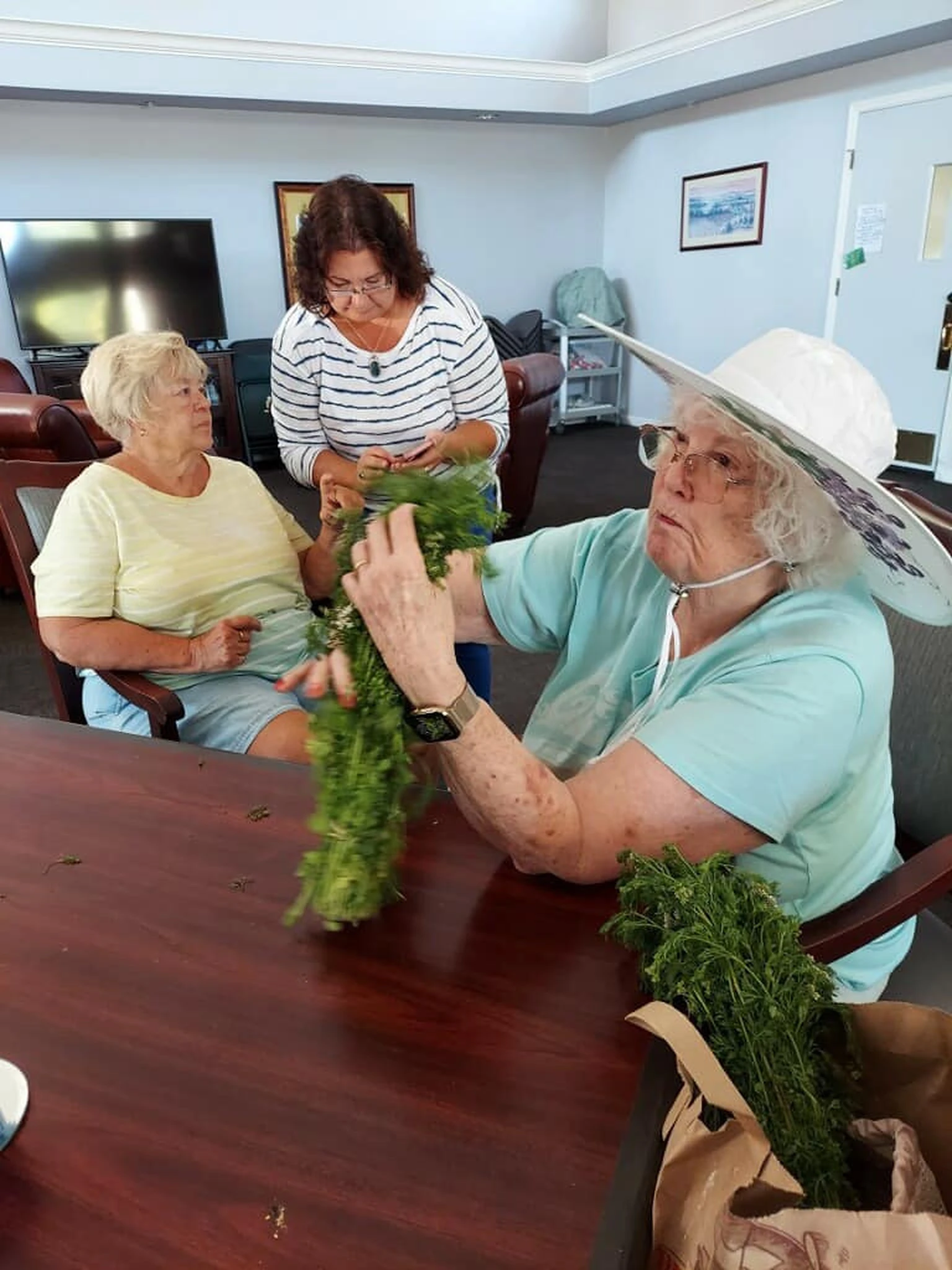 Residents work with greenery around a table during a senior community activity.