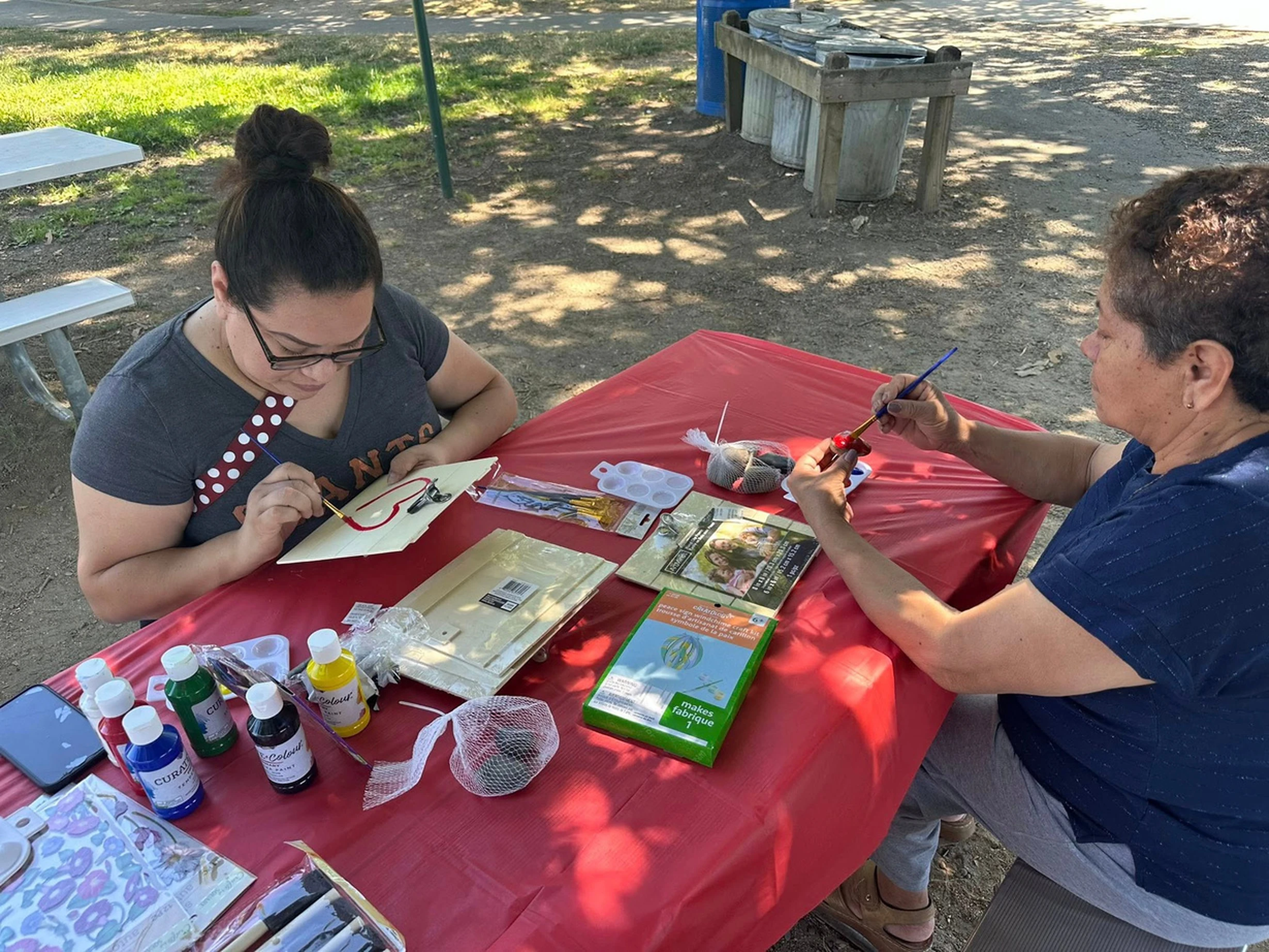 Two residents paint at an outdoor table during Art in the Park.
