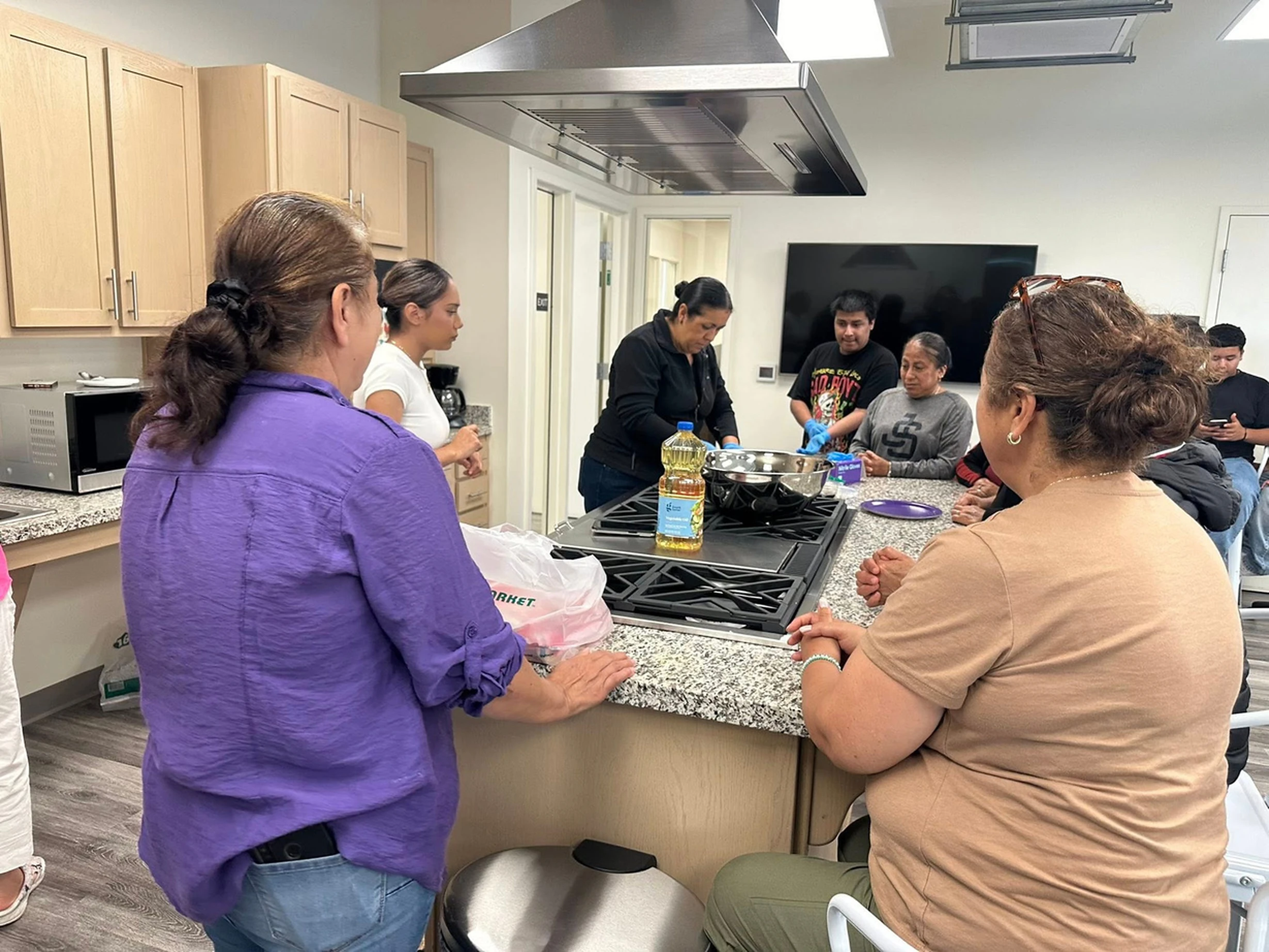 Residents gather around a kitchen island for a cooking class.